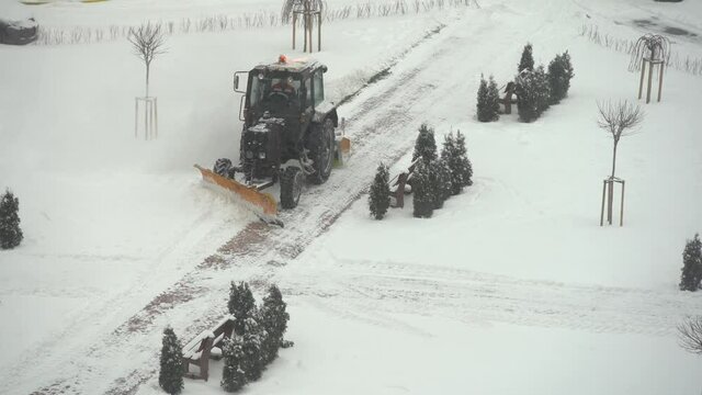 tractor-excavator removes snow in the city yard. work of public utilities