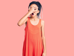 Cute african american girl wearing casual clothes peeking in shock covering face and eyes with hand, looking through fingers with embarrassed expression.