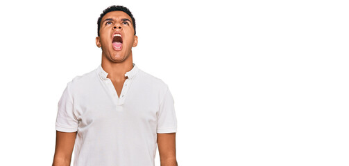 Young arab man wearing casual clothes angry and mad screaming frustrated and furious, shouting with anger. rage and aggressive concept.