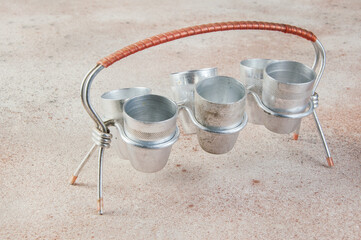 Old aluminum small cups with a stand on concrete background.