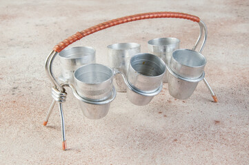 Old aluminum small cups with a stand on concrete background.