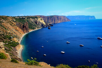 Fototapeta premium Beautiful blue Cape Fiolent in Crimea (Ukraine) with seaside landscape and small boats in the see