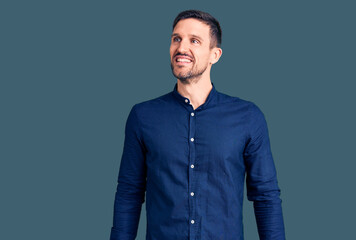Obraz premium Young handsome man wearing casual shirt looking away to side with smile on face, natural expression. laughing confident.