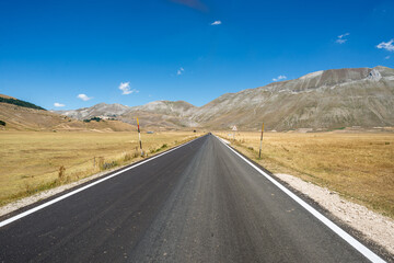 Naklejka premium Empty road crossing the fields in Castelluccio di Norcia, Umbria, Italy