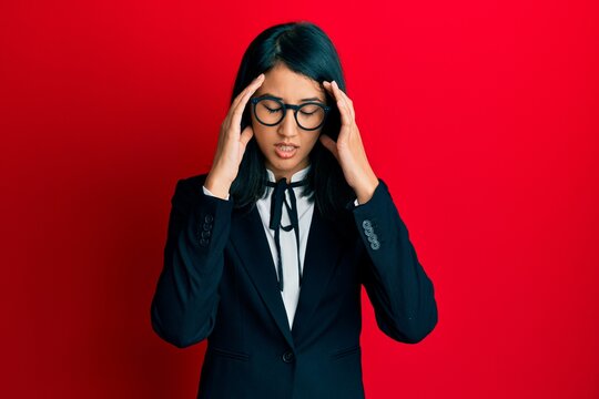 Beautiful asian young woman wearing business suit with hand on head for pain in head because stress. suffering migraine.