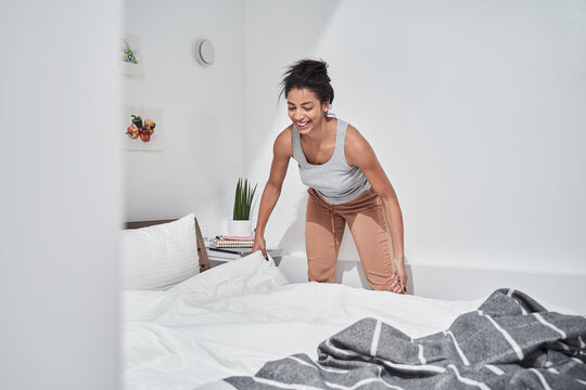 Woman making her bed early in the morning at home
