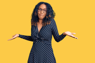 Young african american woman wearing casual clothes and glasses clueless and confused expression...