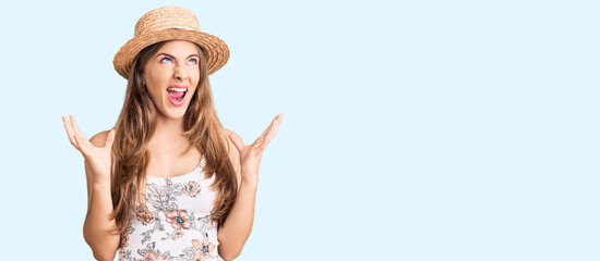 Obraz na płótnie Canvas Beautiful caucasian young woman wearing summer hat crazy and mad shouting and yelling with aggressive expression and arms raised. frustration concept.