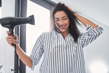 Happy woman drying her hair in bathroom at home
