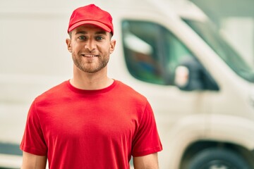 Young caucasian deliveryman smiling happy standing at the city.