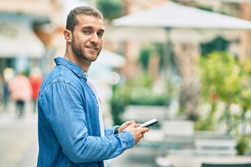 Young caucasian man smiling happy using smartphone at the city.