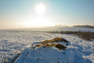 Fototapeta premium Dung heap with snow , sun and landscape