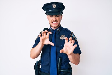 Young caucasian man wearing police uniform smiling funny doing claw gesture as cat, aggressive and sexy expression