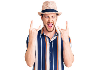 Naklejka premium Young handsome caucasian man wearing summer hat shouting with crazy expression doing rock symbol with hands up. music star. heavy concept.