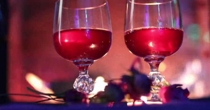 two glasses with red wine on the background of fire in the fireplace, Valentine's Day