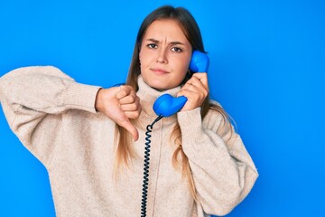 Beautiful caucasian woman speaking on vintage telephone with angry face, negative sign showing...