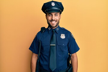 Handsome hispanic man wearing police uniform with a happy and cool smile on face. lucky person.