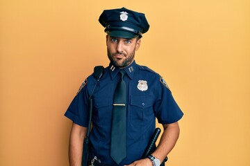 Handsome hispanic man wearing police uniform skeptic and nervous, frowning upset because of...
