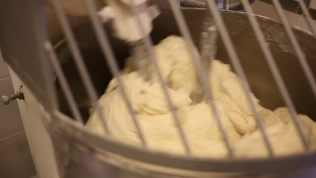 Closeup of kneading machine preparing dough for baking bread in baker workshop. High quality FullHD footage