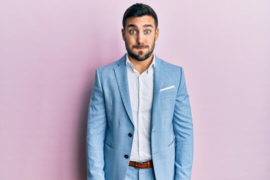 Young hispanic businessman wearing business jacket puffing cheeks with funny face. mouth inflated with air, crazy expression.