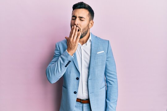 Young hispanic businessman wearing business jacket bored yawning tired covering mouth with hand. restless and sleepiness.