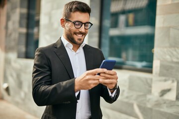 Young hispanic businessman smiling happy using smartphone at the city.