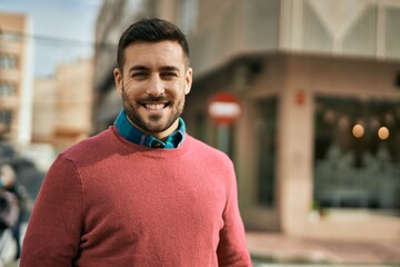 Young hispanic man smiling happy standing at the city.