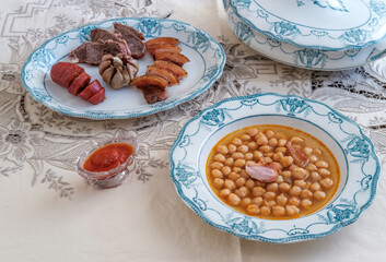 Spanish Chickpea Stew with meat. Elegant crockery. Traditional table. Embroidered tablecloth. Cooking chickpea. Winter dishes. 