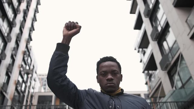 A young African American man rasises his first in solidarity for social and racial justice. Peaceful protest for equality and positive change. Black lives matter 4k
