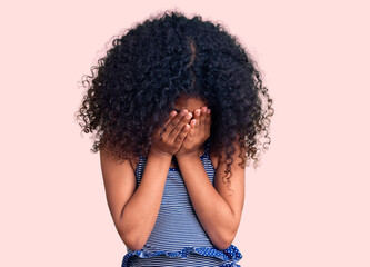 African american child with curly hair wearing swimwear with sad expression covering face with...