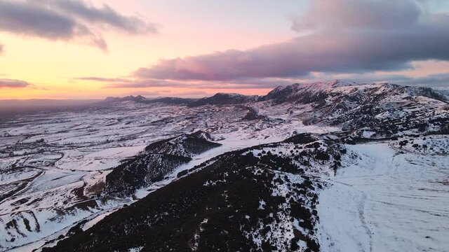 Aerial view over snow covered high mountains at sunset. High quality 4k footage
