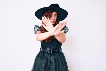 Young beautiful woman wearing witch halloween costume rejection expression crossing arms doing negative sign, angry face
