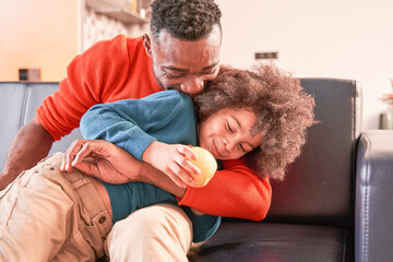 Boy sitting with his father at the sofa at home