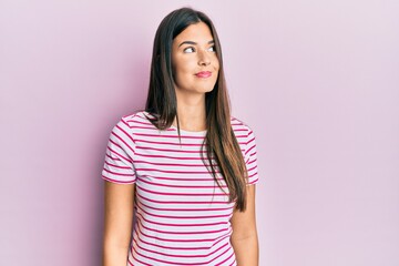 Fototapeta premium Young brunette woman wearing casual clothes over pink background smiling looking to the side and staring away thinking.