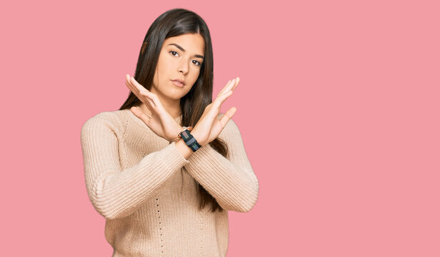 Young brunette woman wearing casual winter sweater rejection expression crossing arms doing negative sign, angry face