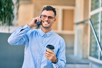 Young hispanic businessman talking on the smartphone and drinking coffee at the city.