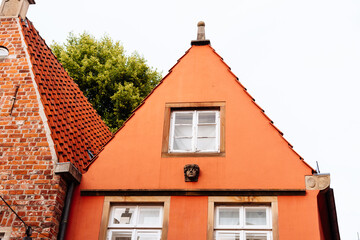 Redstone house with a red tile roof, an ornamental carved stone face on the facade