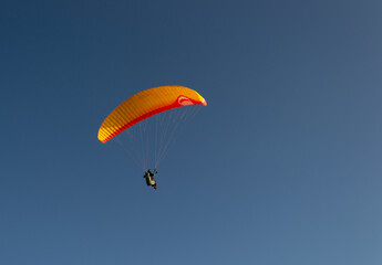 A beautiful view of a paraglide flying gliding on a clear blue sky at the golden hour with a nice wind windy breeze on a sunny day 