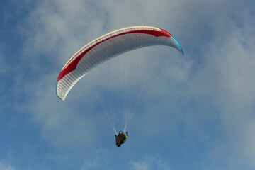 A beautiful view of a paraglide flying gliding on a clear blue sky at the golden hour with a nice wind windy breeze on a sunny day 