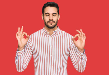 Fototapeta premium Young hispanic man wearing business shirt relax and smiling with eyes closed doing meditation gesture with fingers. yoga concept.