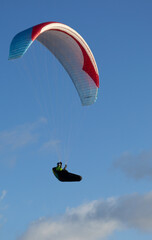 A beautiful view of a paraglide flying gliding on a clear blue sky at the golden hour with a nice wind windy breeze on a sunny day 