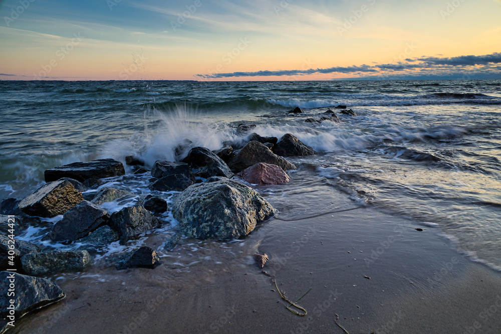 Wall mural Beautiful shot of waves crashing on the rocks at the beach at sunset