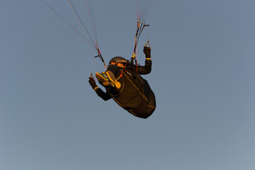 A beautiful view of a paraglide flying gliding on a clear blue sky at the golden hour with a nice wind windy breeze on a sunny day 