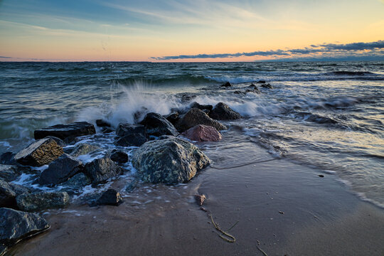 Beautiful shot of waves crashing on the rocks at the beach at sunset