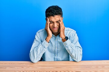 Fototapeta premium Young handsome african american man wearing casual clothes sitting on the table with hand on head, headache because stress. suffering migraine.