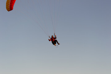 A beautiful view of a paraglide flying gliding on a clear blue sky at the golden hour with a nice wind windy breeze on a sunny day 