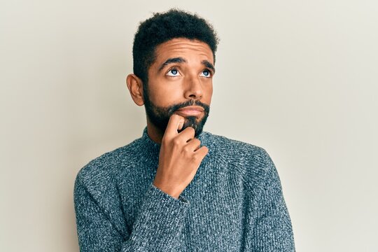 Handsome hispanic man with beard wearing casual clothes thinking concentrated about doubt with finger on chin and looking up wondering