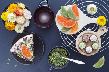 Cake with coffee, sweets, pumpkin seeds and flowers on a dark background. Selective focus