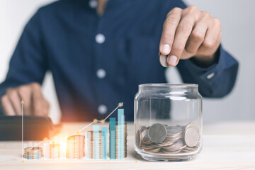 Fototapeta na wymiar businessman holding coins putting in glass. concept saving money for finance accounting to arrange coins into growing graphs concept.