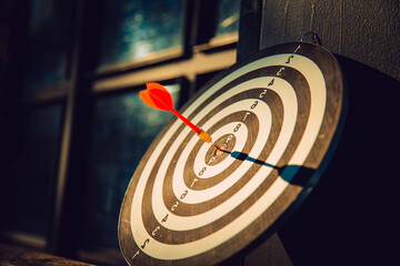 Dart arrow hit on bulleyes of dartboard to represent that the business reached the target  with...